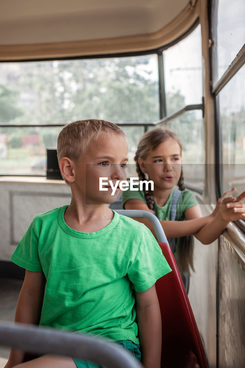 Kids ride in empty tram and look at the window with interest, public transportation, city tramway