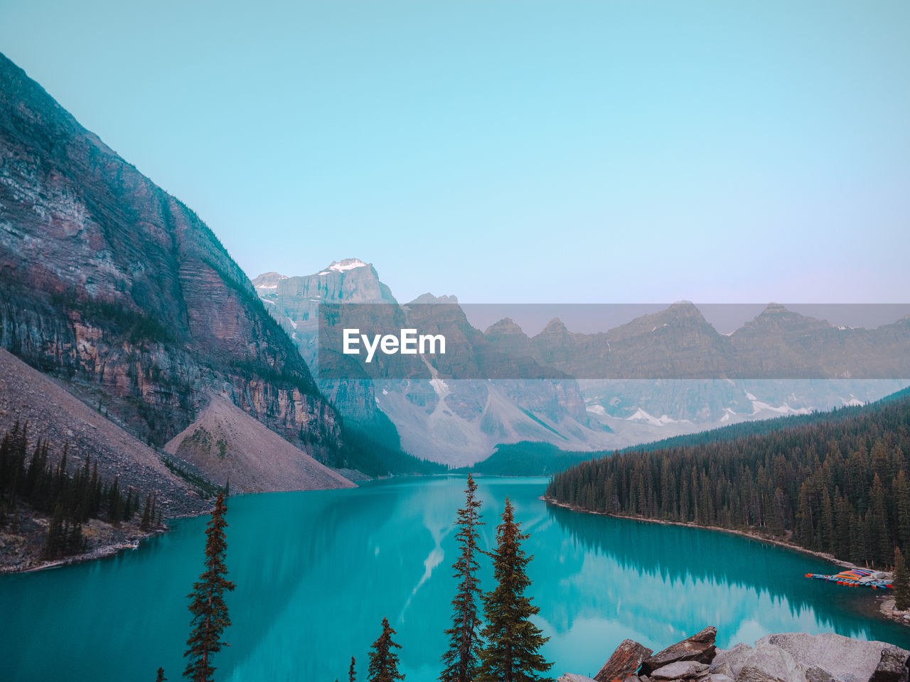 Scenic view of lake by mountains against clear blue sky