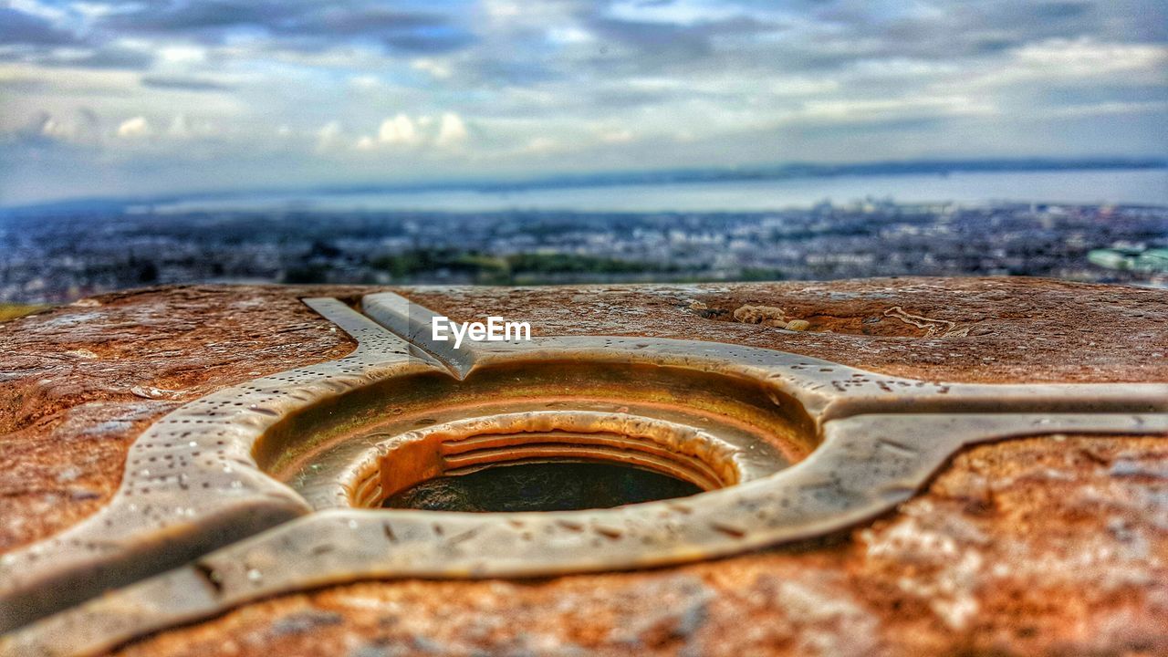 Close-up of hole in metal against cloudy sky