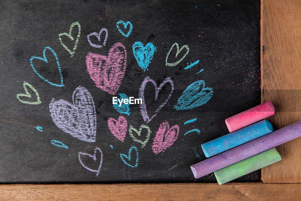 Close-up of colorful heart shape chalk drawings on blackboard