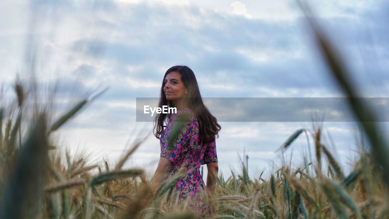 Portrait of smiling young woman standing on field