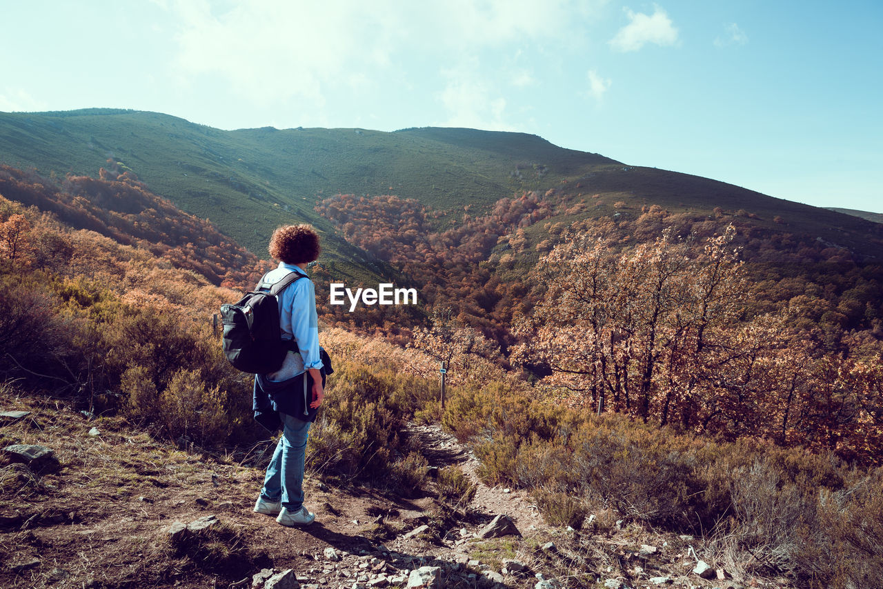 Full length of backpacker looking at mountains against sky