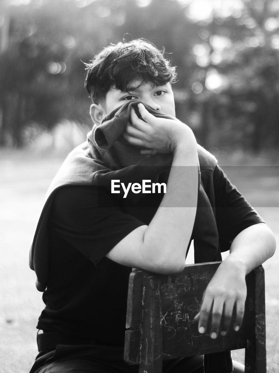 Young man looking away while sitting outdoors