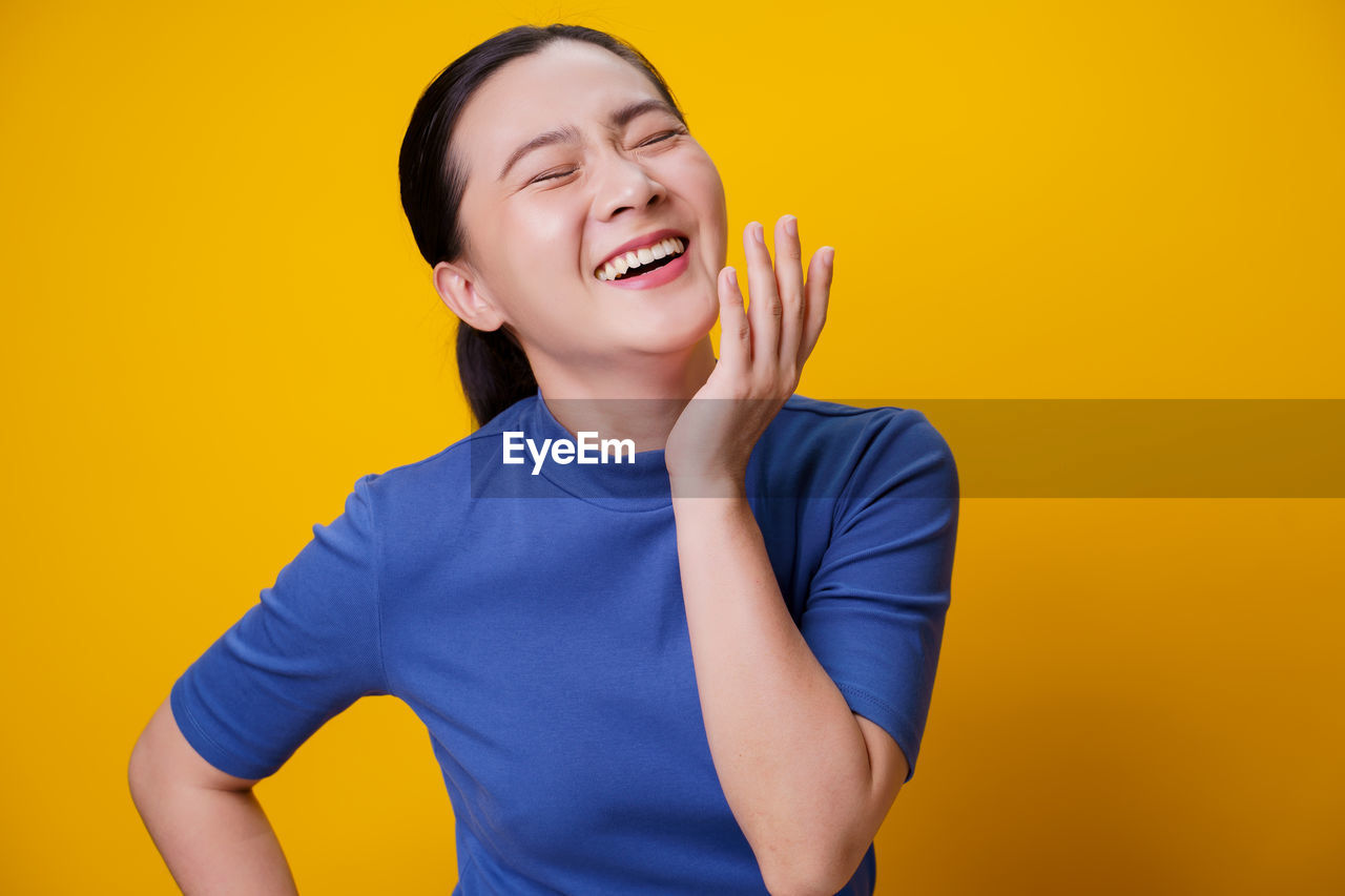 MID ADULT MAN STANDING AGAINST YELLOW BACKGROUND