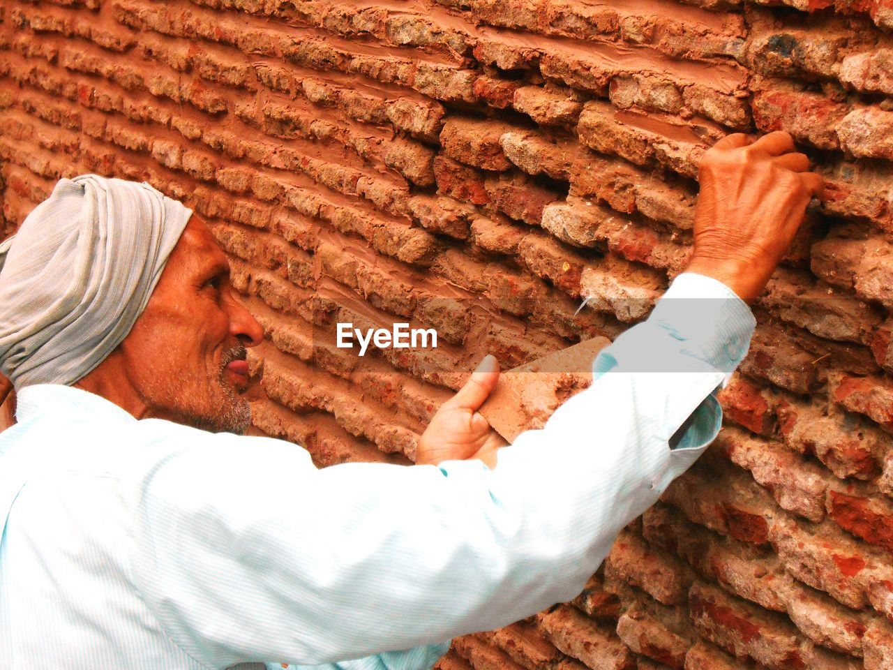Side view of senior man touching stone wall