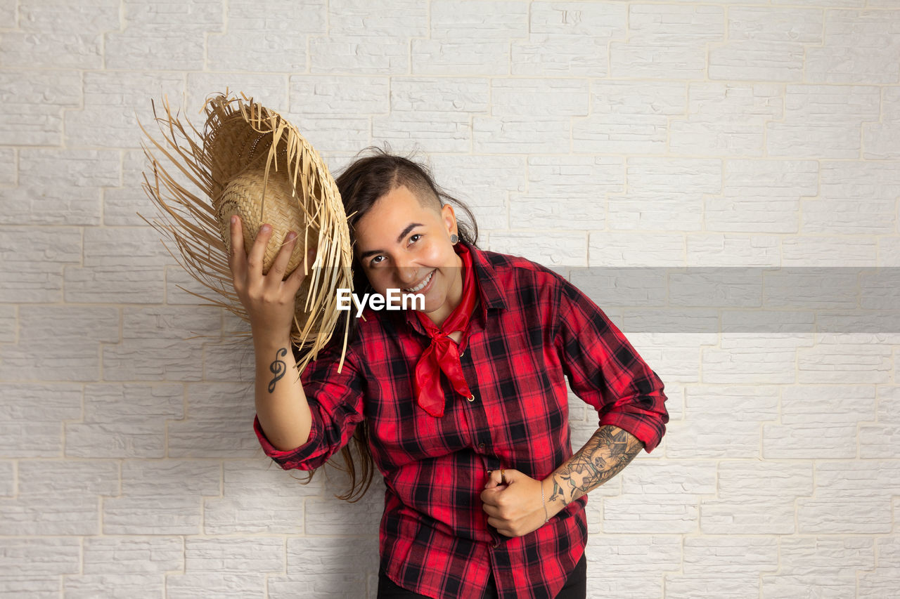 Hipster woman holding hat against wall