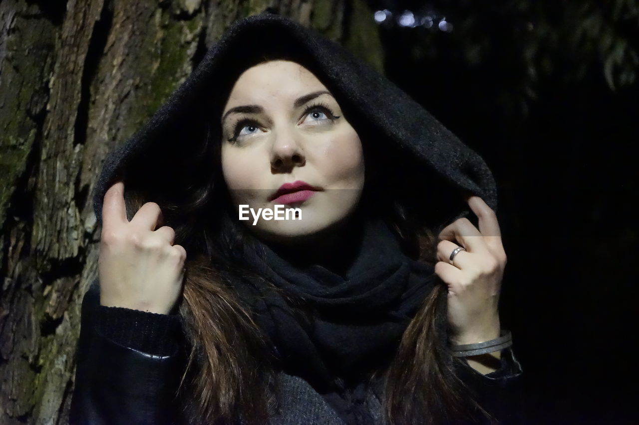 Close-up of beautiful young woman wearing hood in forest