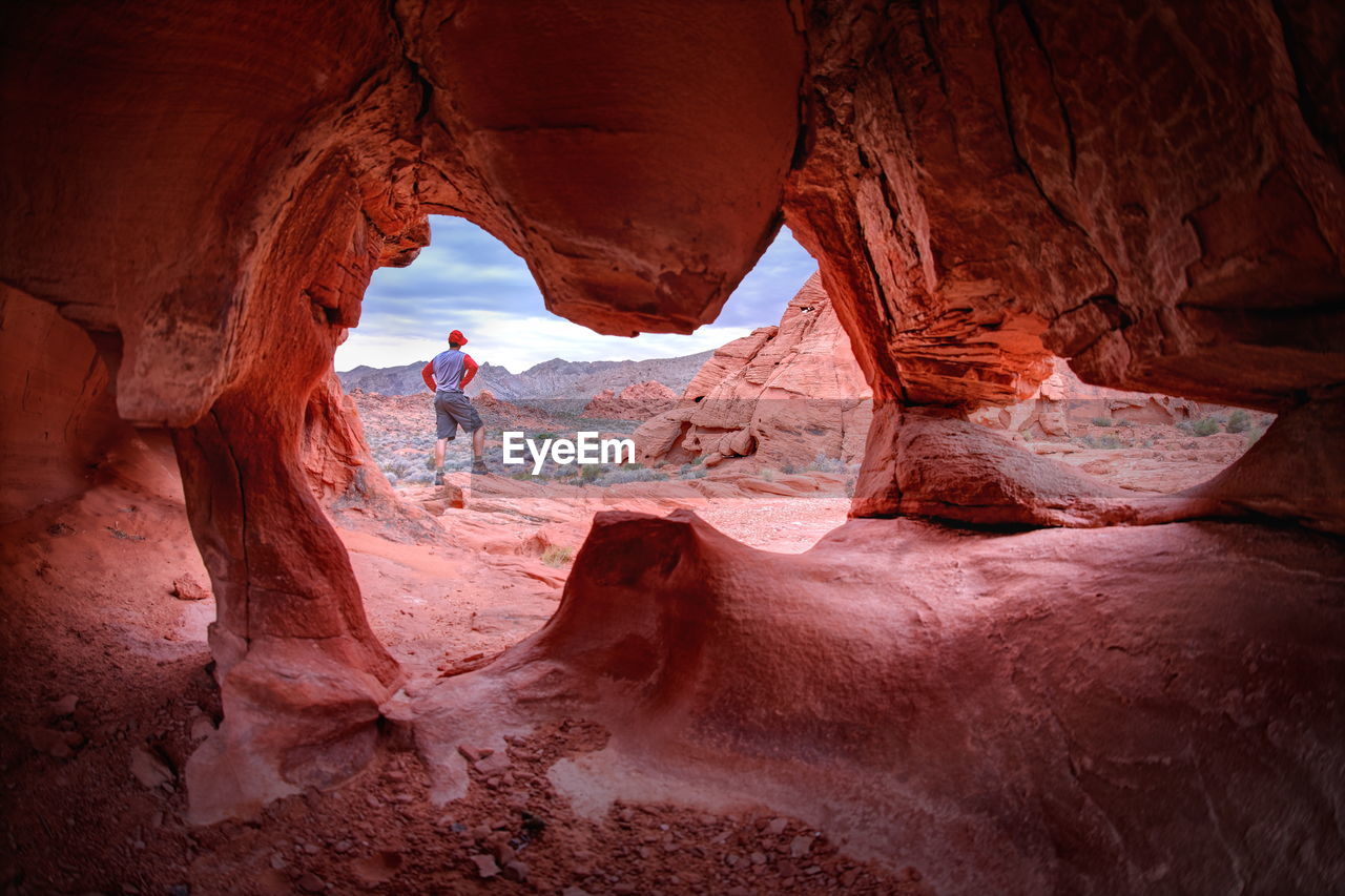 Rear view of man standing on rock seen from cave at valley of fire state park