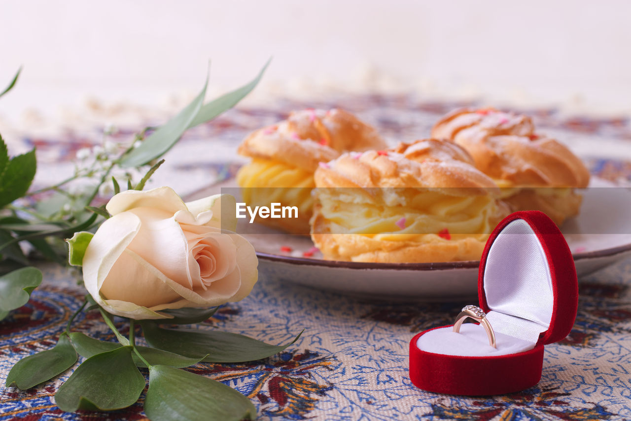 Low angle close-up of flower and ring with desserts in background.celebrate valentine with your love
