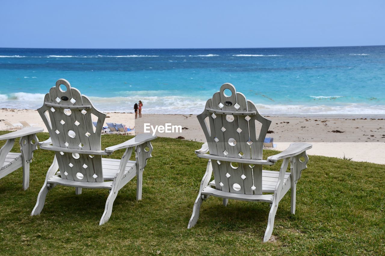 CHAIRS AND TABLE ON BEACH AGAINST SKY