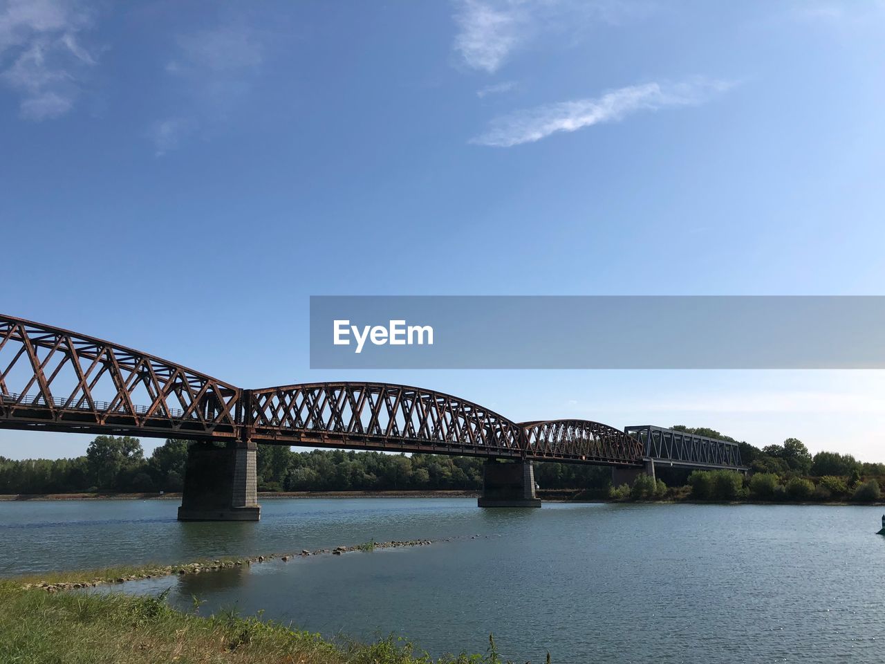 BRIDGE OVER CALM RIVER AGAINST SKY