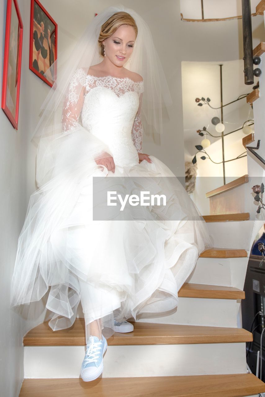 Full length of bride moving down staircase