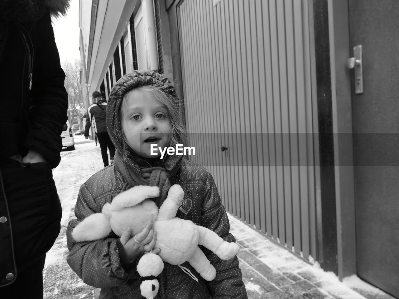 Portrait of girl holding stuffed toy while standing on footpath