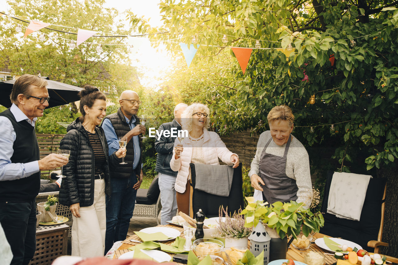 Cheerful senior friends enjoying during back yard dinner party