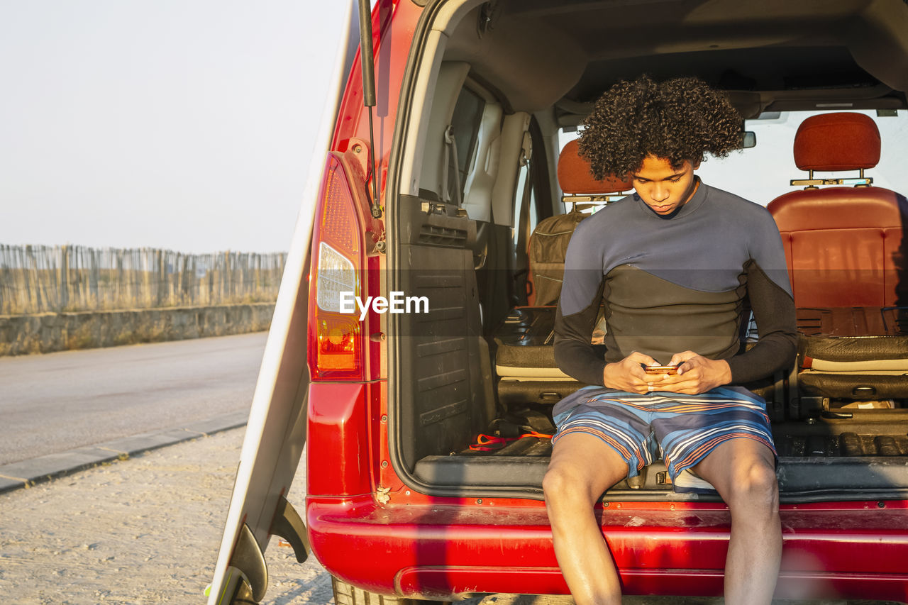 Young latino surfer with afro hair talks on a mobile phone in the caravan person