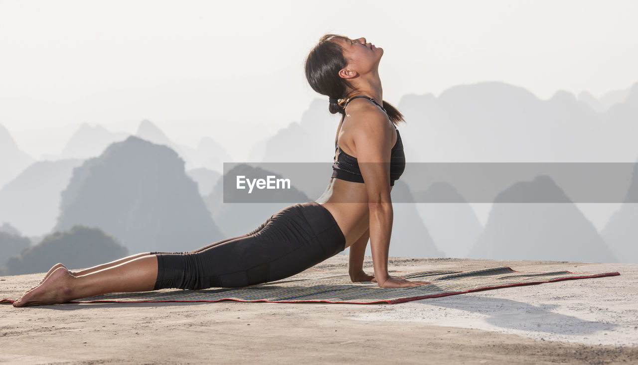 Beautiful woman practising yoga above the kast mountains of yangshuo