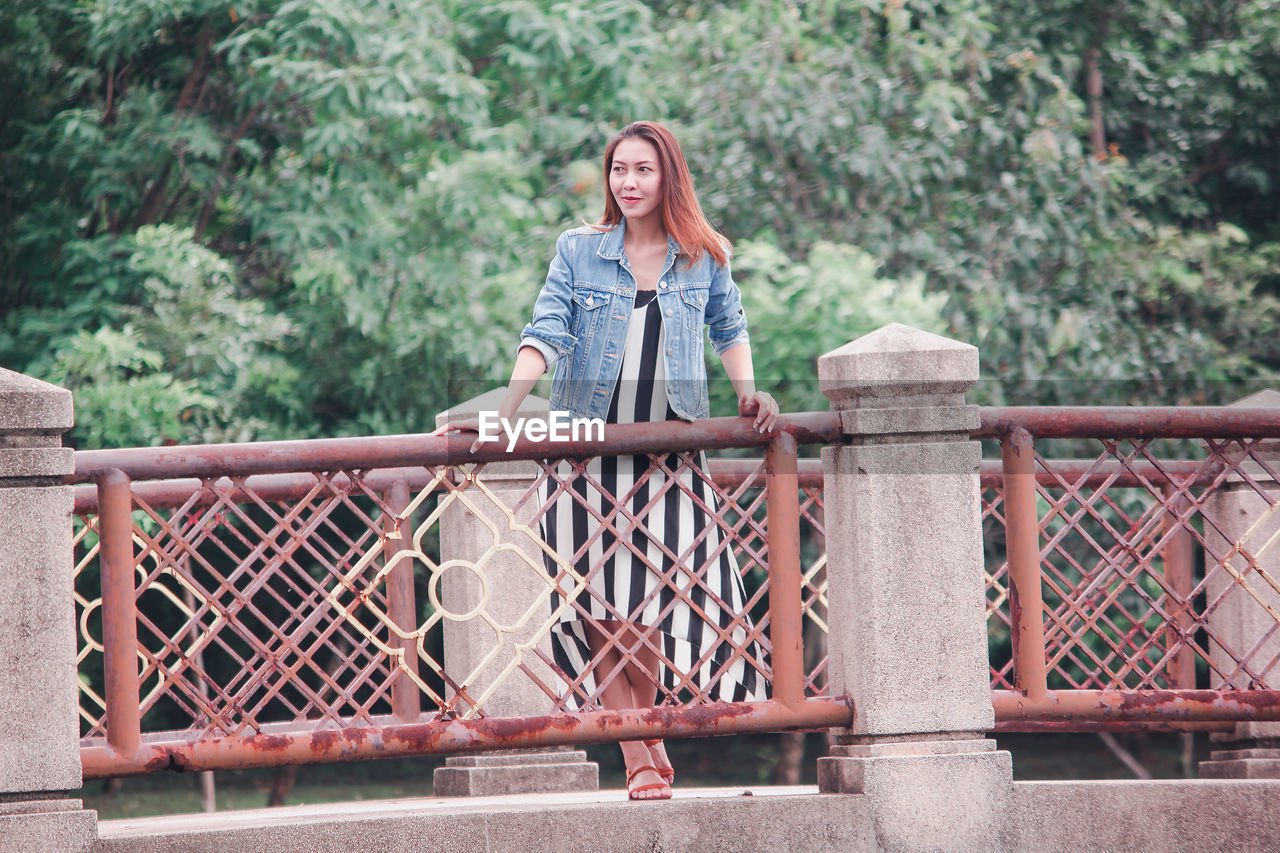 Woman looking away while standing on footbridge