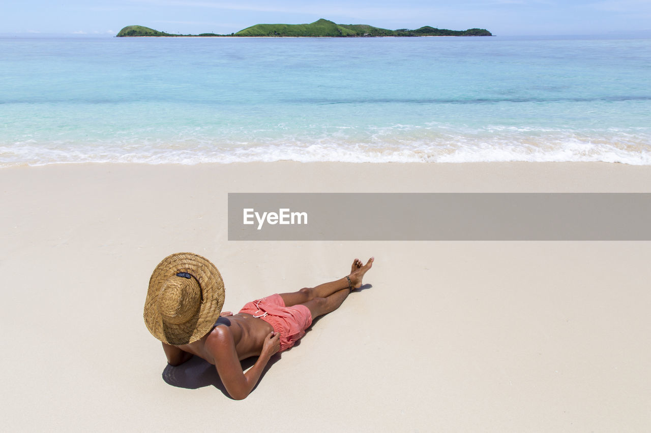 One male tourist, wearing pink swuimsuits, on idyllic sandbank of fiji