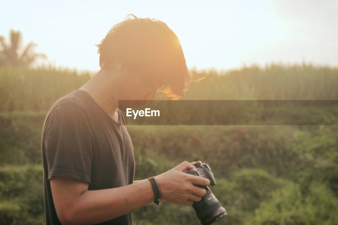 Young man using camera on field