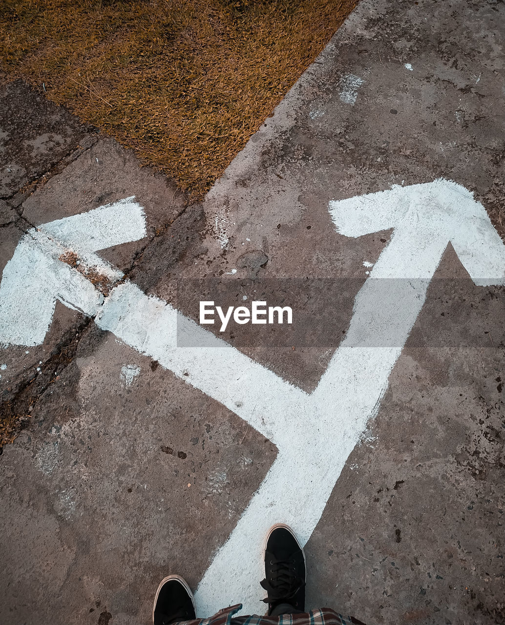 Low section person standing by arrow symbol on road