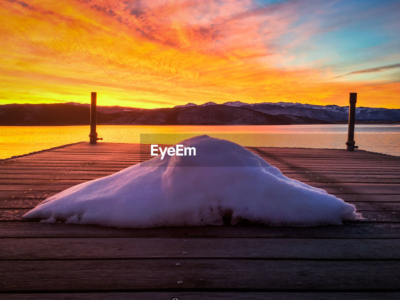 Close-up of snow on pier against sky during sunset
