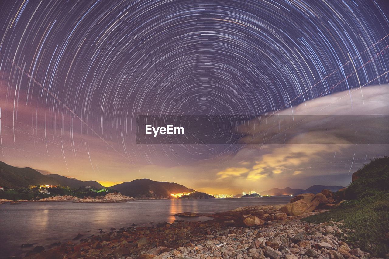 Scenic view of river against star trails at dusk