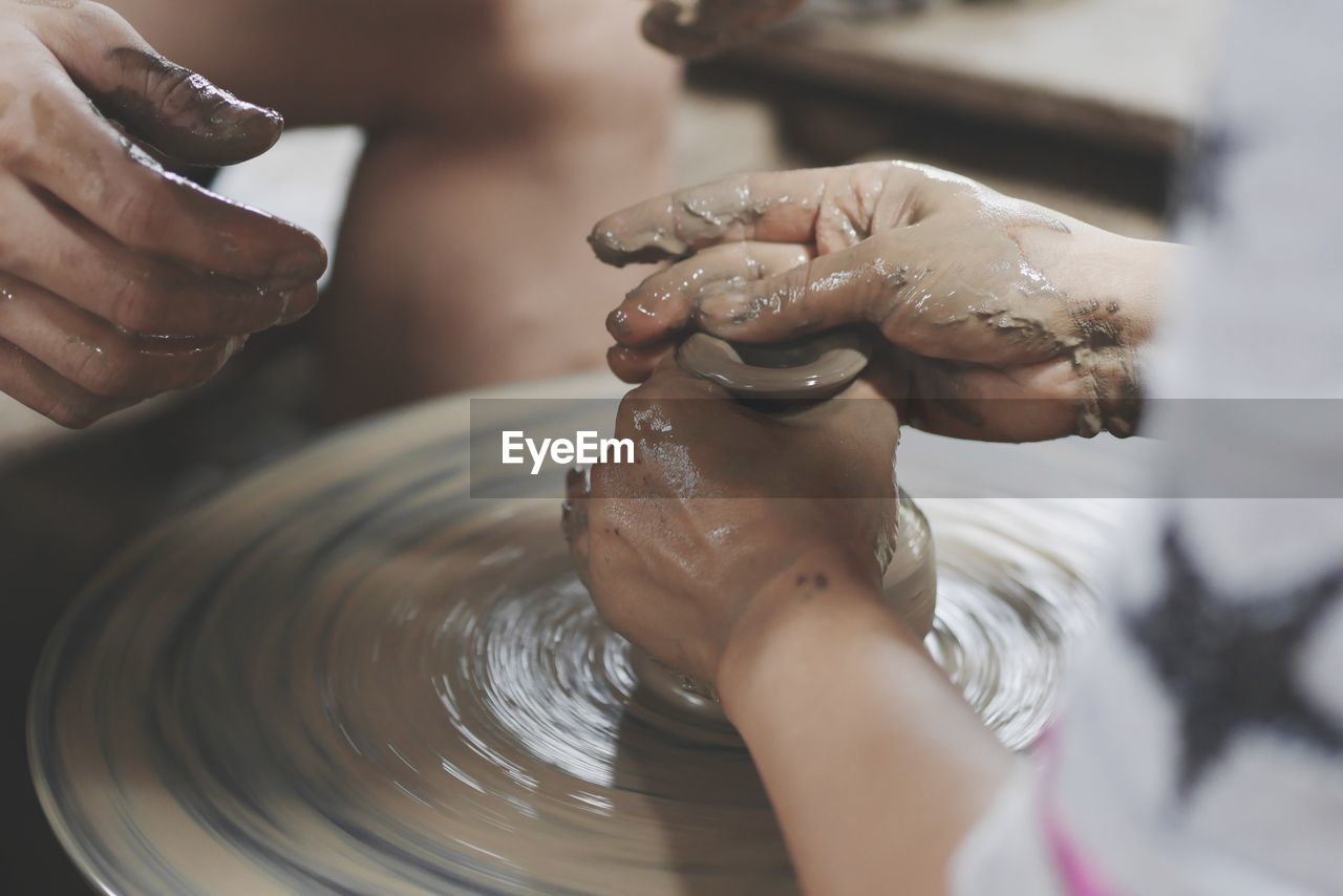 Cropped image of people working on pottery wheel