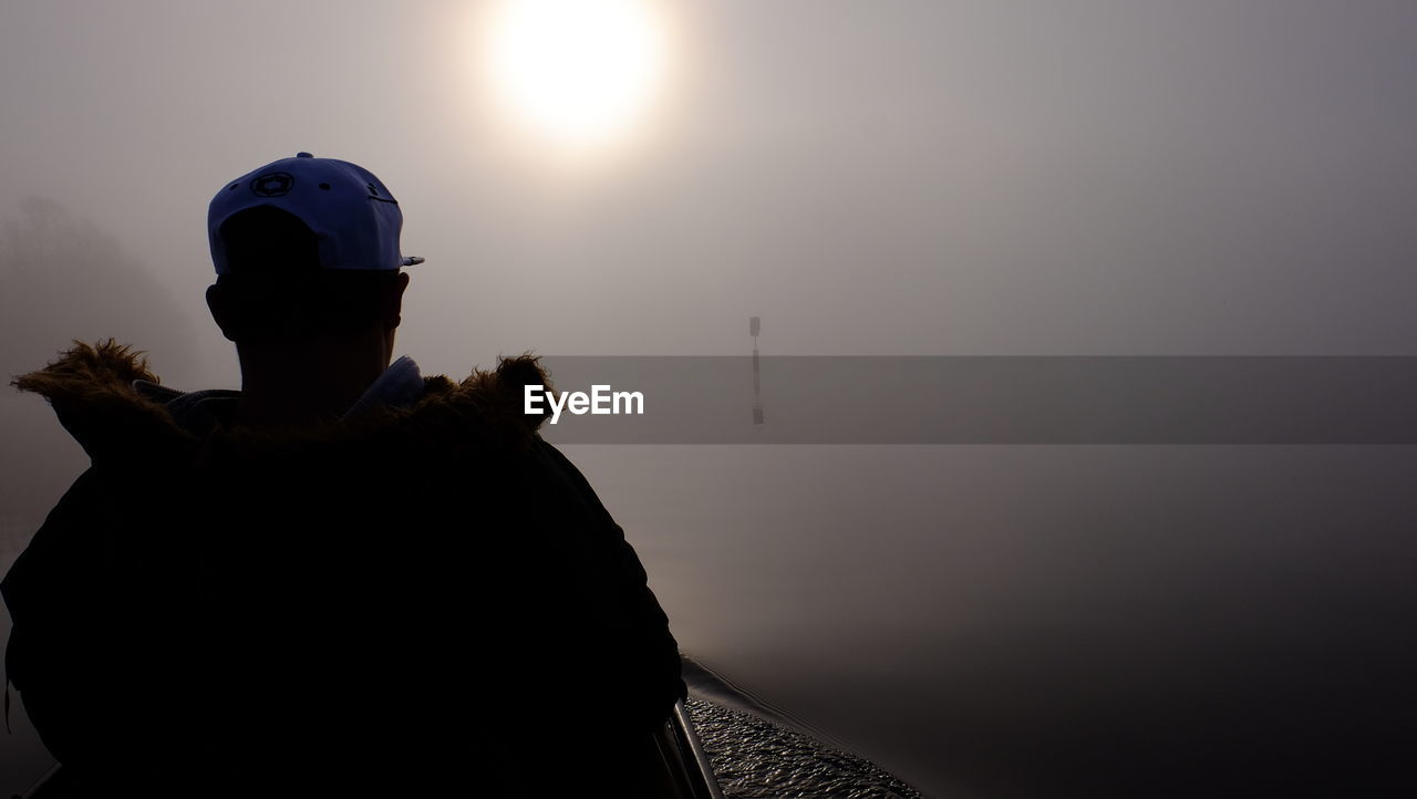 Rear view of man standing against sky during sunset