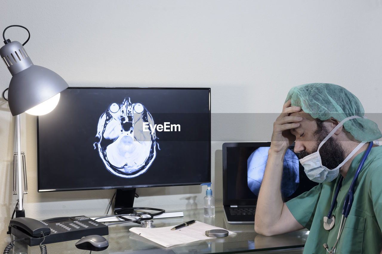 Worried doctor with head in hands sitting at table