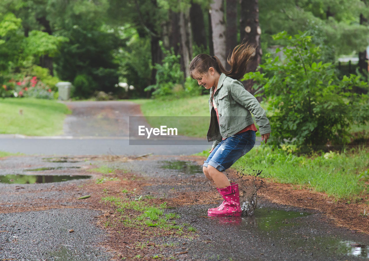 Young girl jumping into puddle