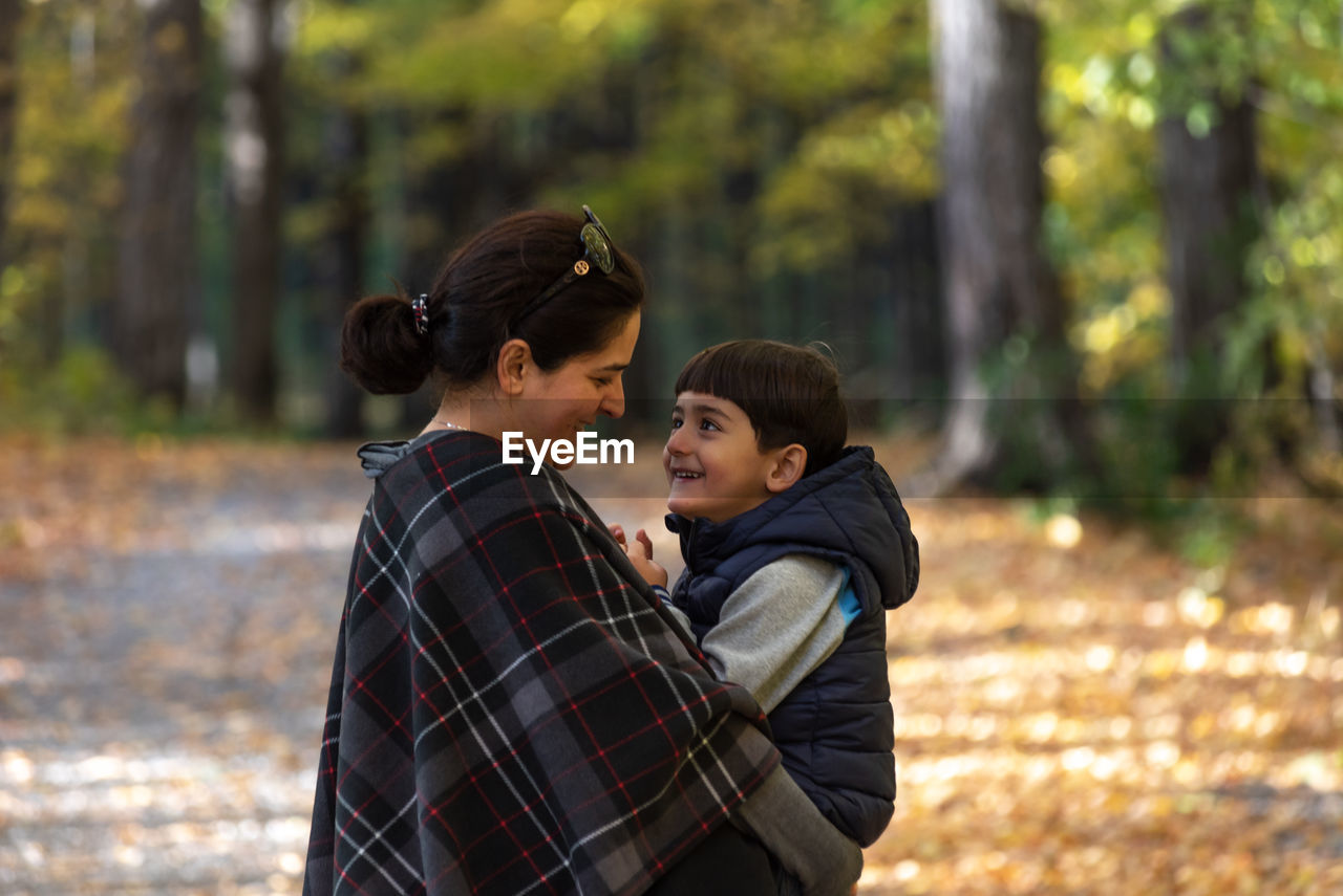 Side view of mother and son embracing while standing at park