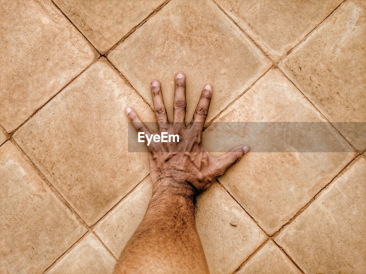 Cropped image of hand on tiled floor