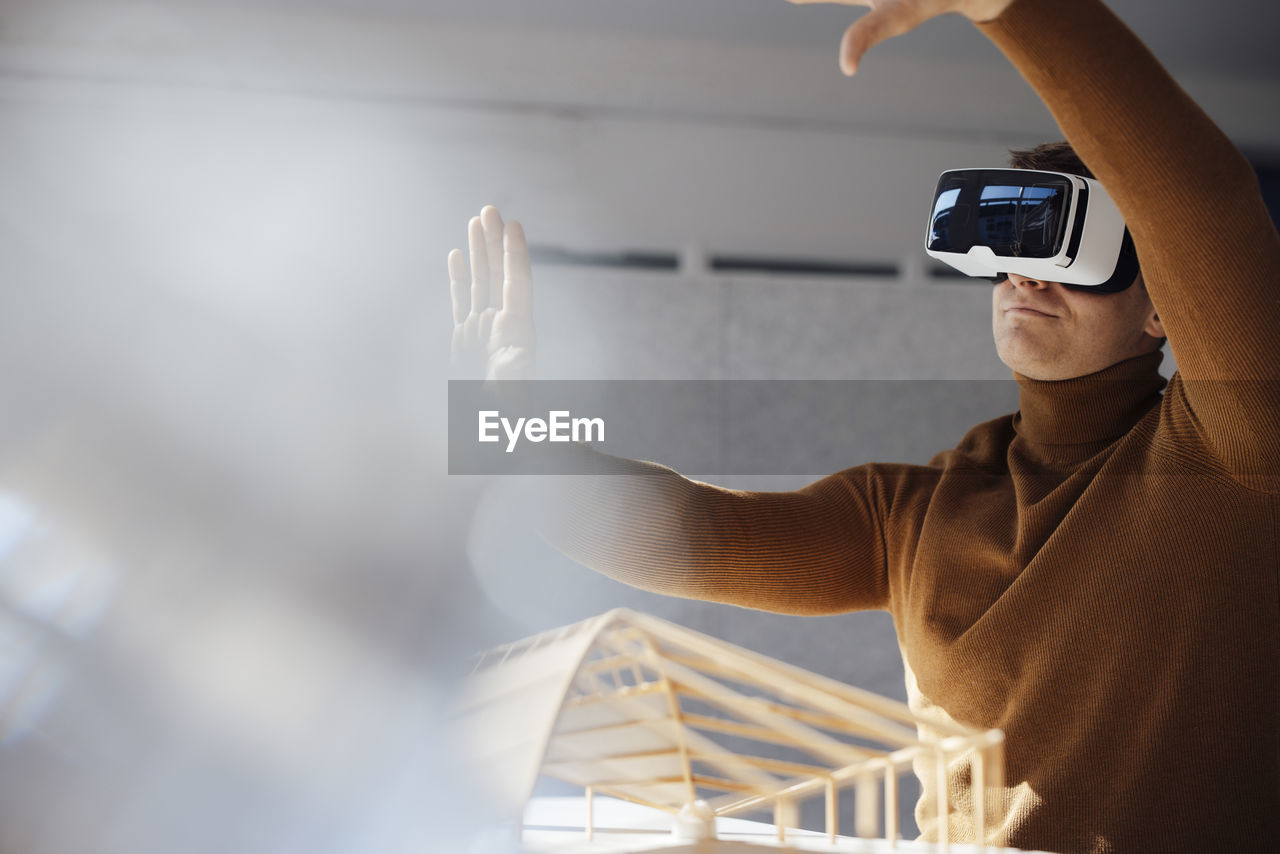 Businessman wearing virtual reality simulator gesturing in office