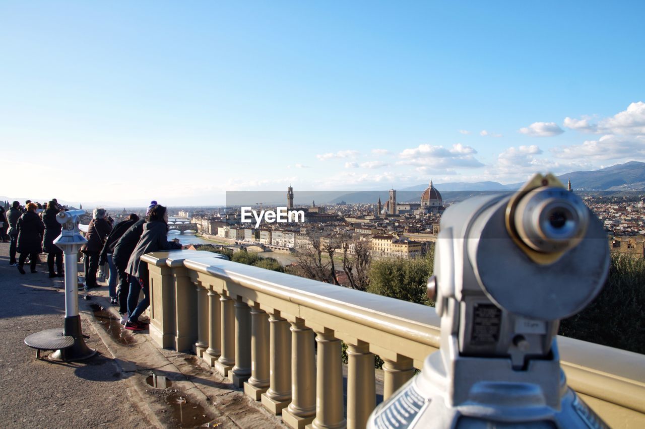 Close-up of hand-held telescope in city against blue sky