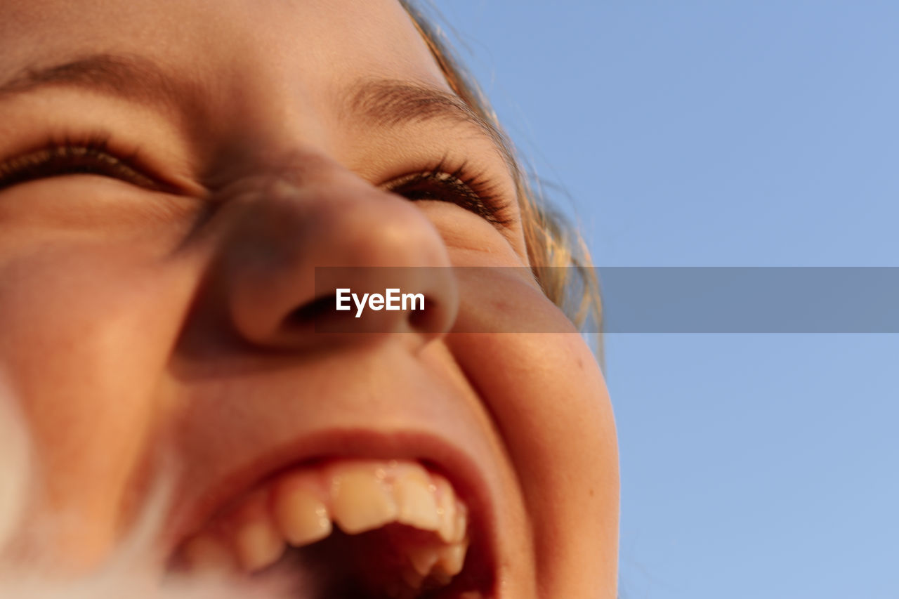 Close-up of happy girl laughing against clear sky