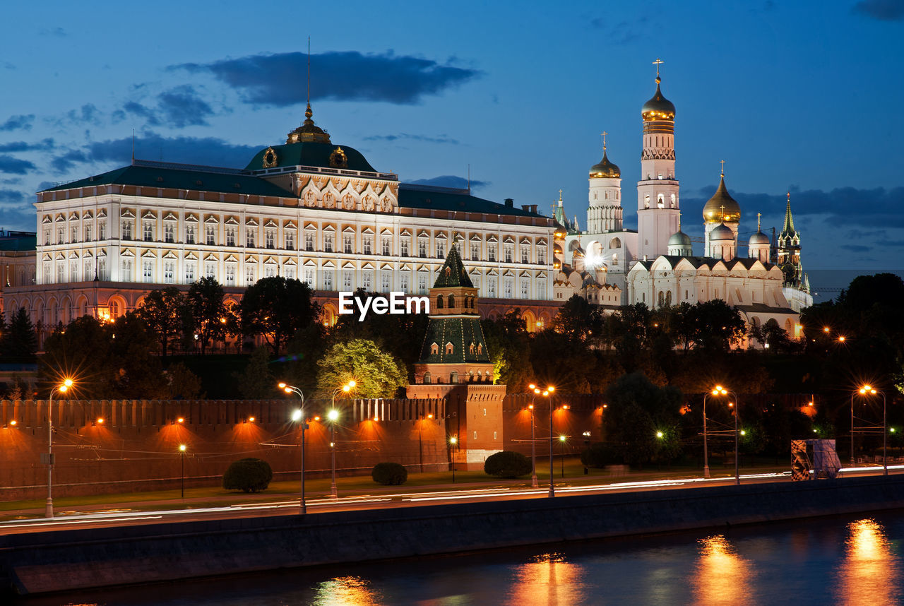 Moscow kremlin by river against sky in city at dusk