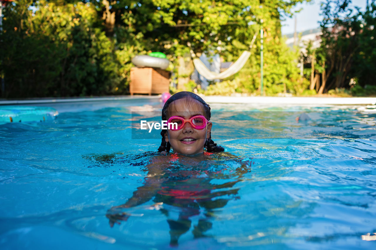 Girl in goggles enjoy training swim at pool in summer camp. active vacation and happy summertime