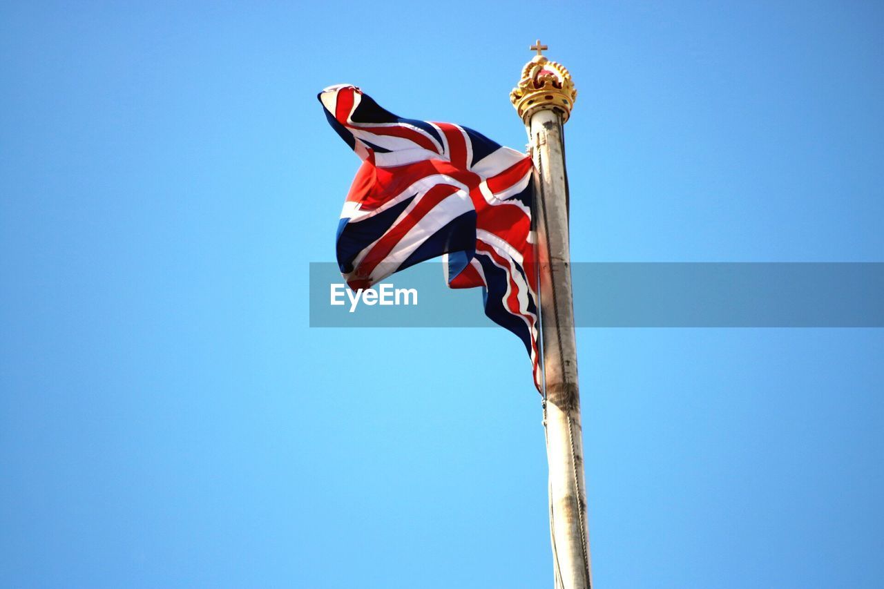 Low angle view of british flag waving against clear blue sky