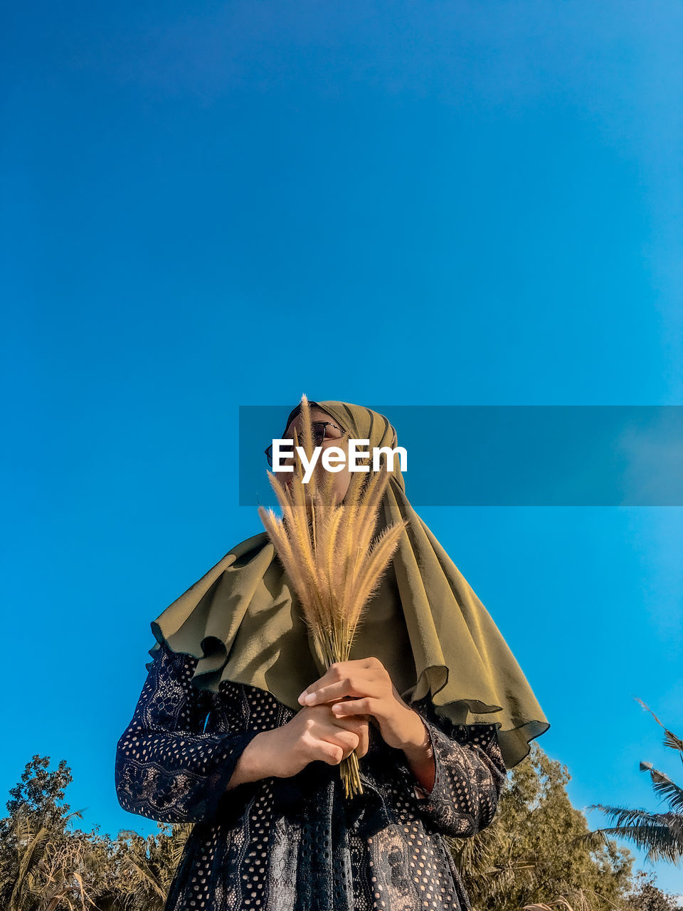 Low angle view of woman standing against blue sky