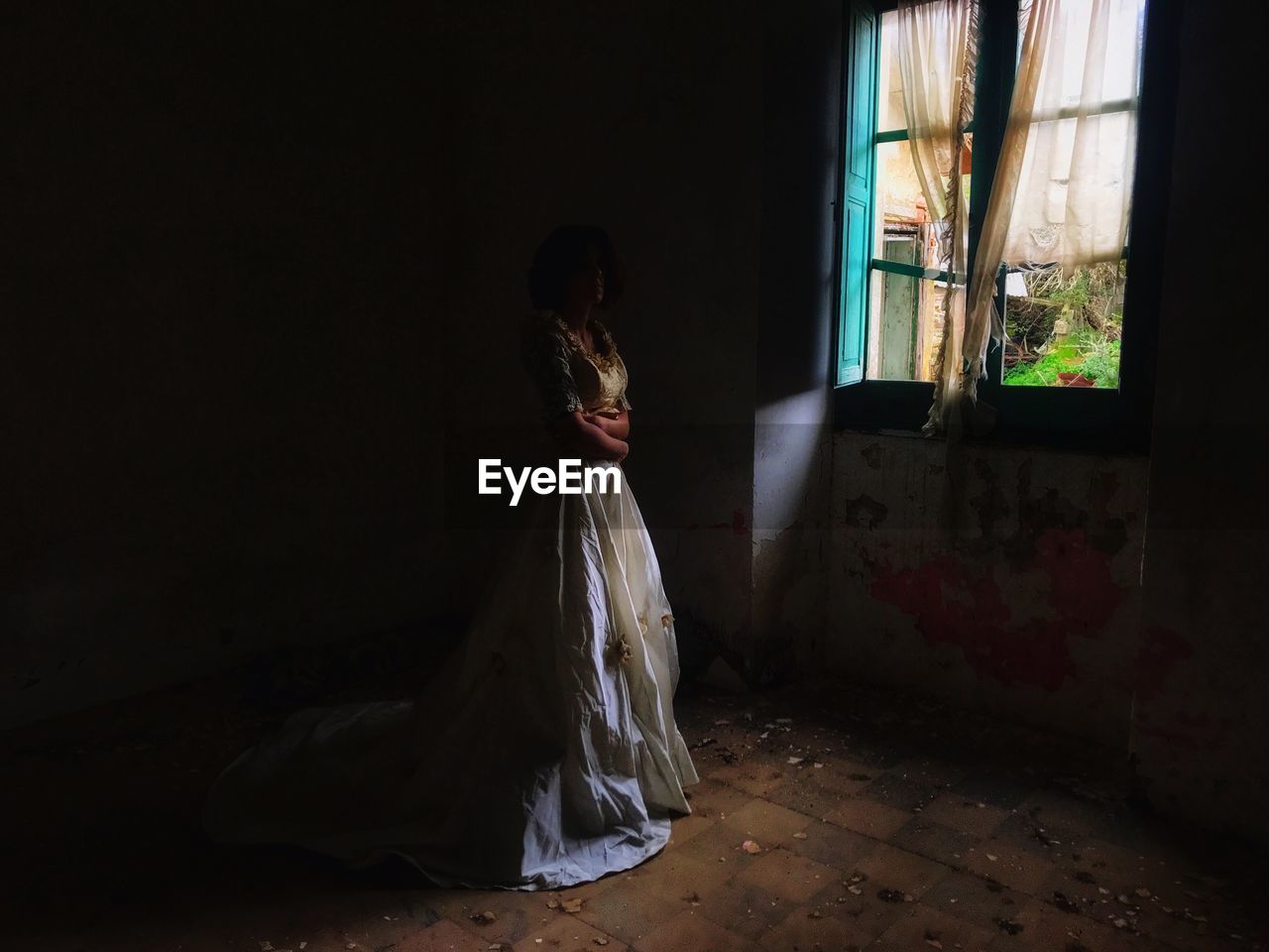 Bride standing on window in abandoned room