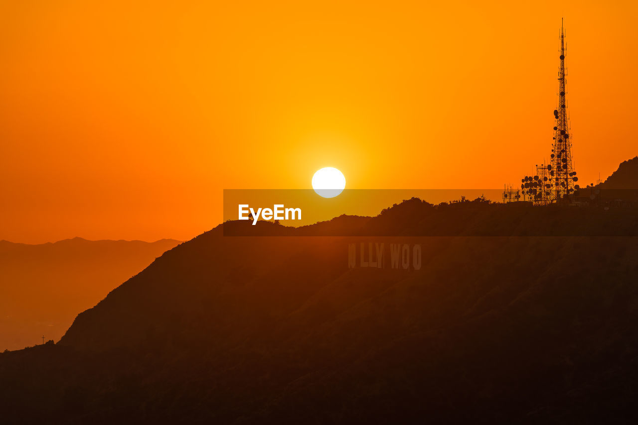 Silhouette buildings against orange sky