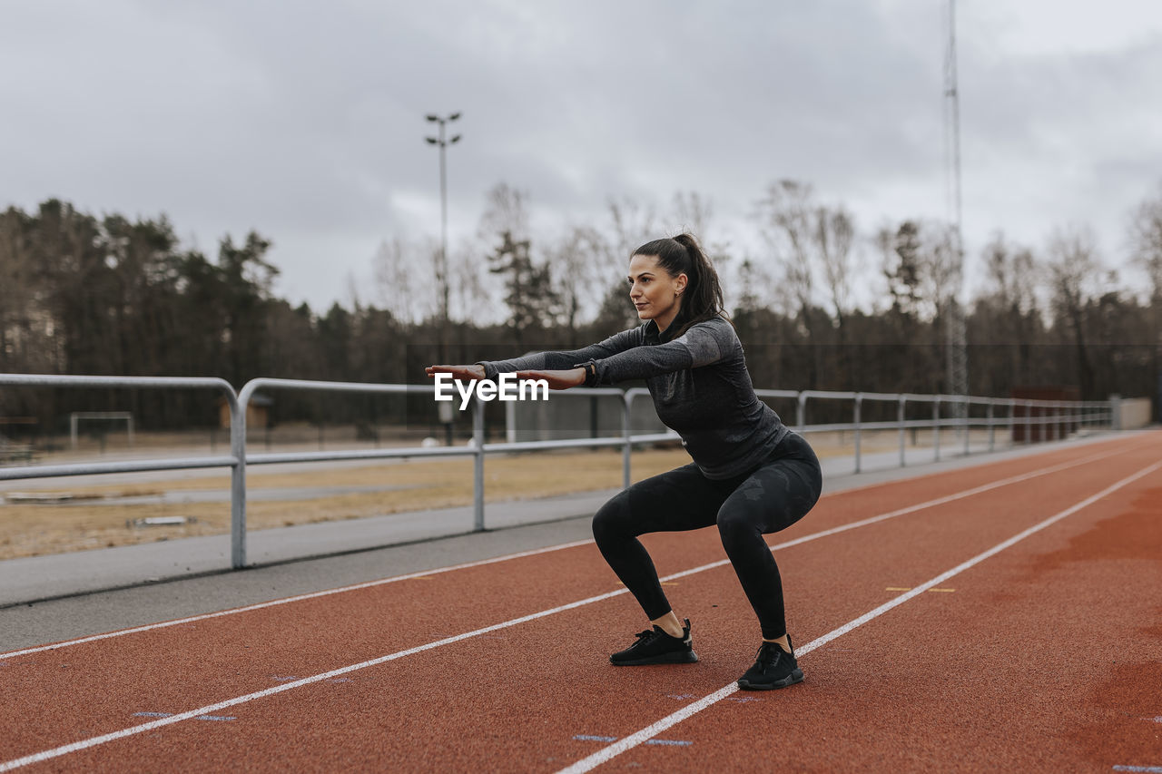 Woman doing squats at running track