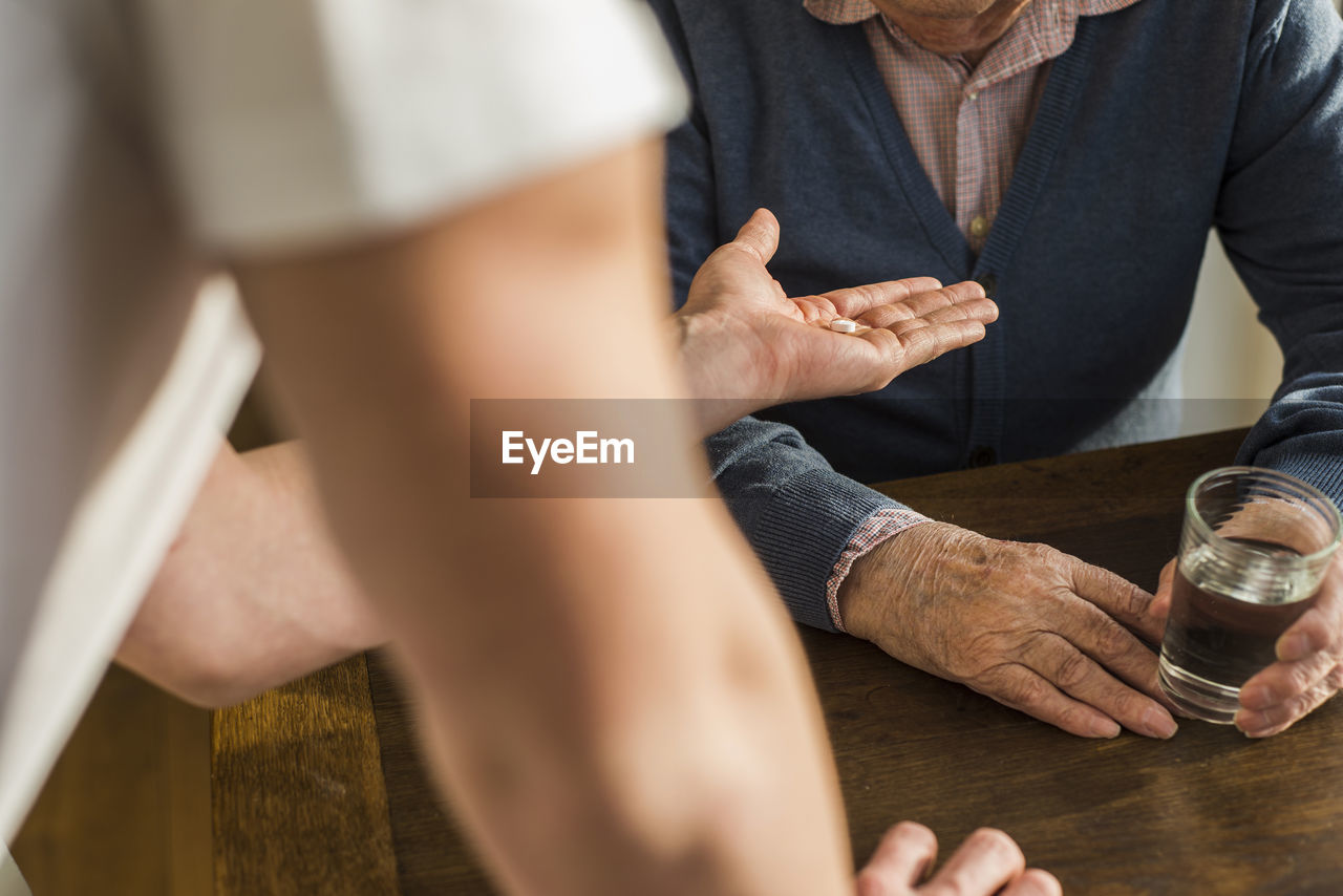 Hand of young man giving senior man his tablet