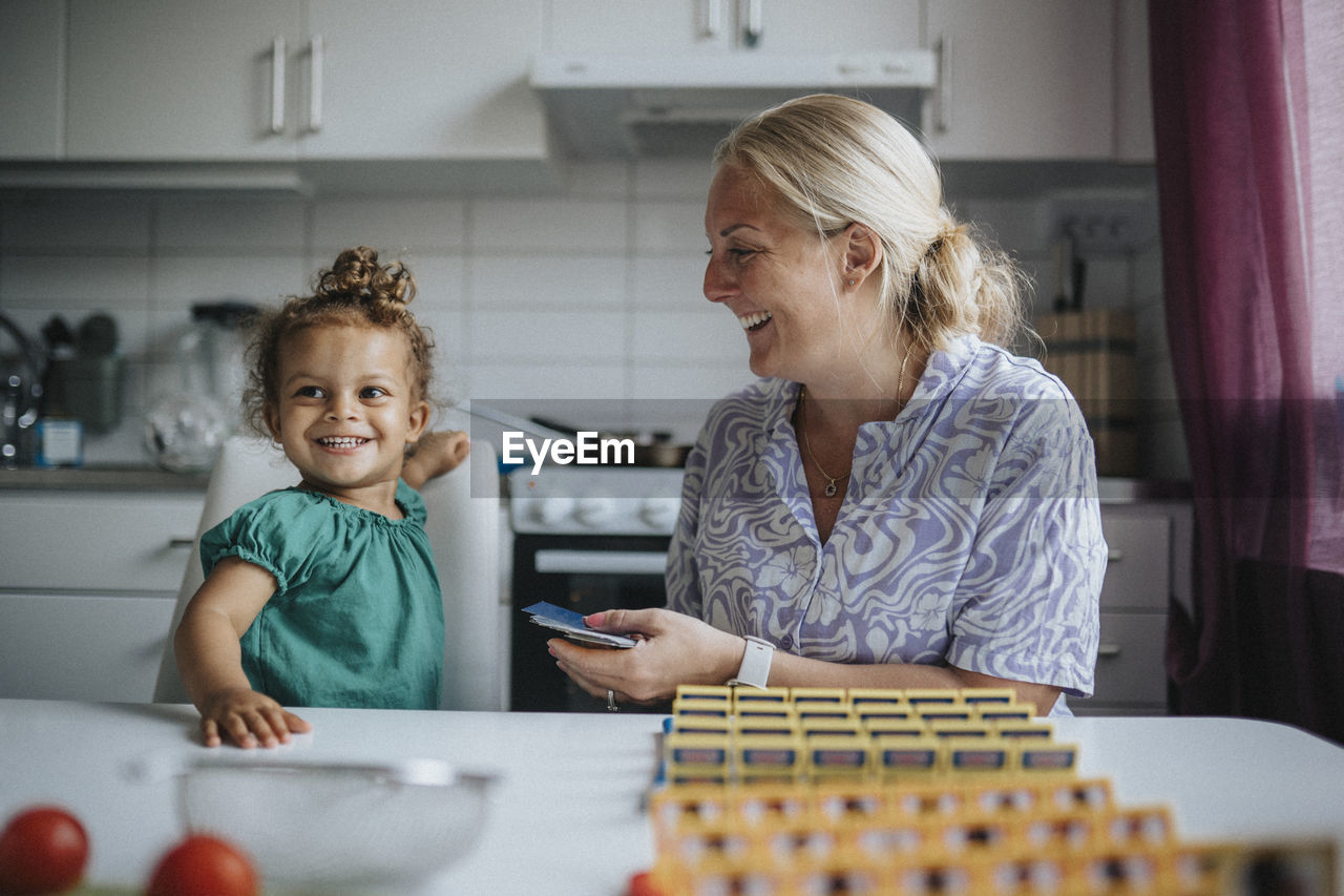 Happy girl playing game with mother at home