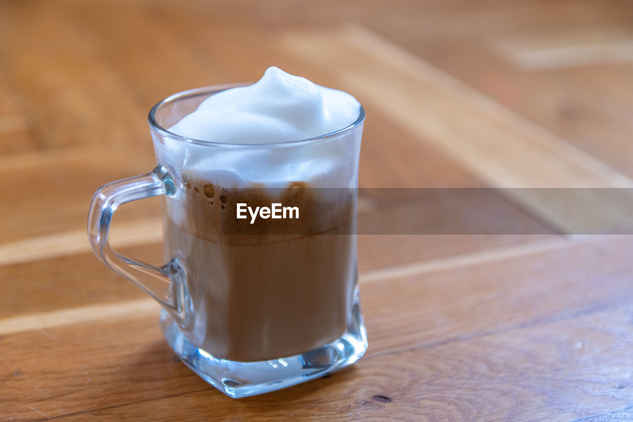 food and drink, drink, refreshment, latte, coffee, table, glass, drinking glass, wood, household equipment, mug, food, hot drink, cup, milk, indoors, dairy, still life, no people, close-up, coffee cup, freshness, cafe, focus on foreground, crockery, coffee milk