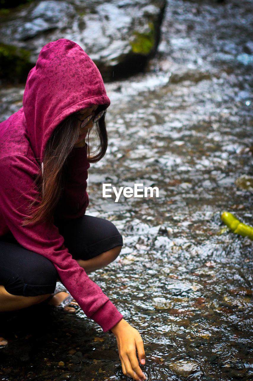 Side view of woman sitting against water