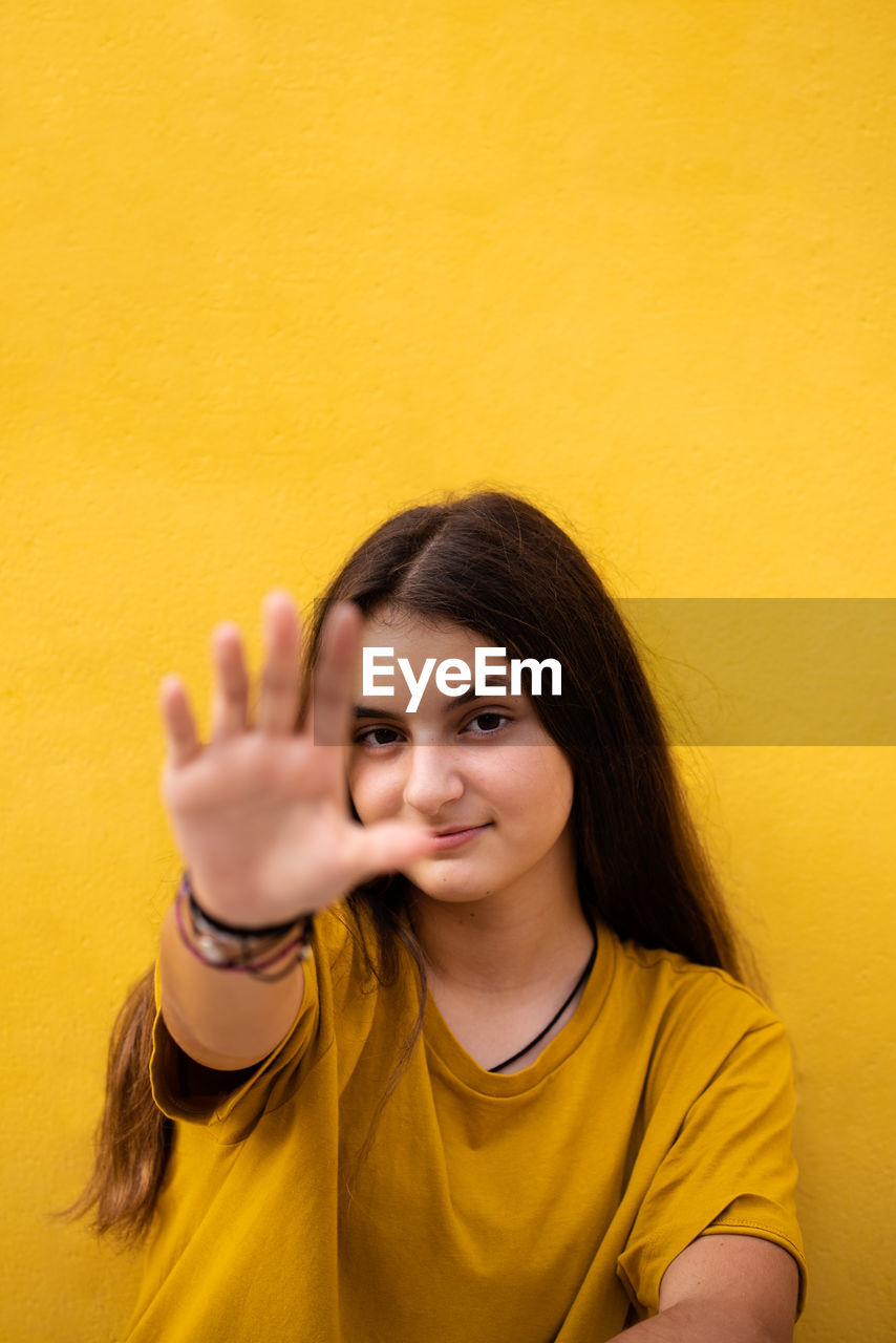 Portrait of young woman against yellow background