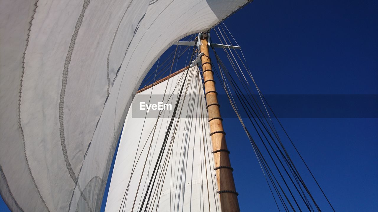 Low angle view of sails against clear blue sky