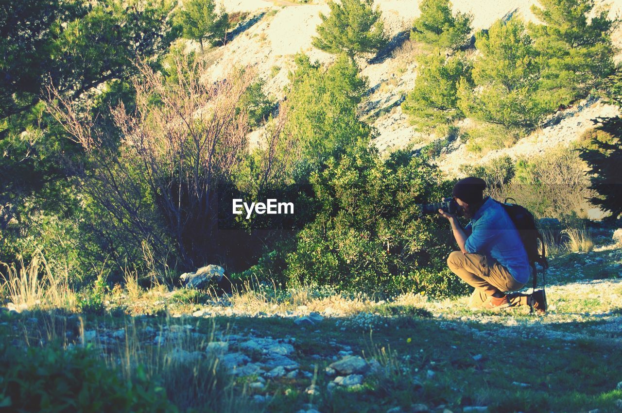 MAN SITTING ON GRASS AGAINST TREE