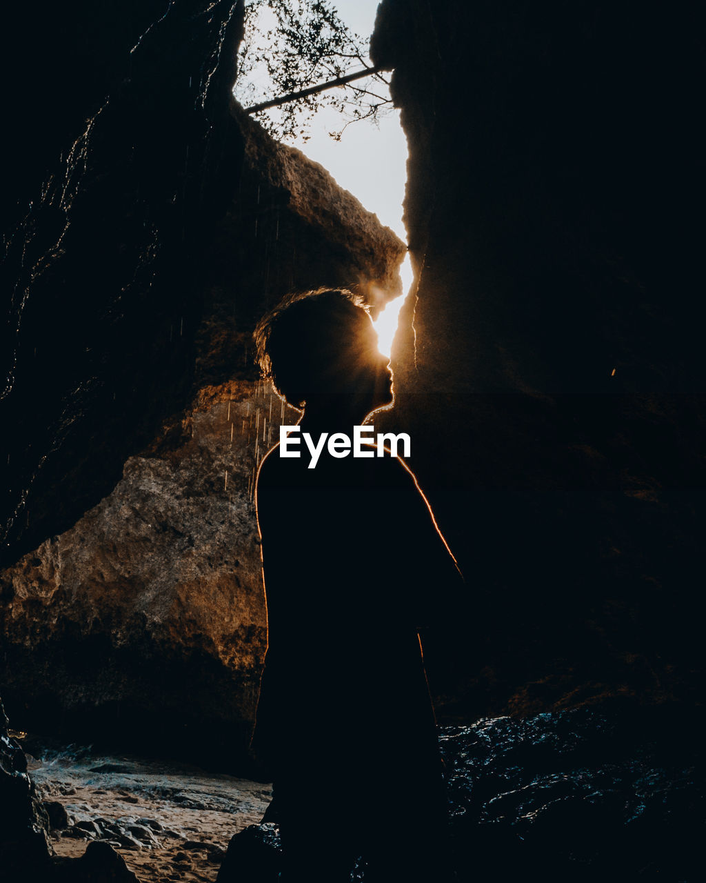 Silhouette man standing by rock against sky